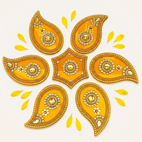 Golden acrylic ornamental rangoli set with intricate beadwork and central gemstone accents for diwali decor