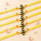 Yellow ribbon animal theme rakhi bracelets with black and white bee charms and orange beads for brother protection gift