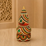 A vibrant multi-tiered artificial mangal kalash decorated with gold red green white beadwork and gemstones for pooja