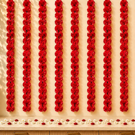 Red artificial carnation garlands hanging vertically as marigold strings for diwali and pooja decoration backdrop