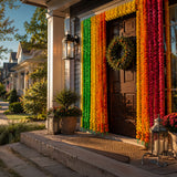 Vibrant rainbow-colored artificial marigold string garlands hanging vertically on wooden door for diwali decoration