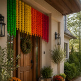 A vibrant rainbow-colored artificial marigold garland hanging above a wooden door for festive decoration