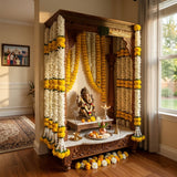 Golden ganesha idol adorned with intricate carvings and draped in artificial white and yellow marigold flower garland