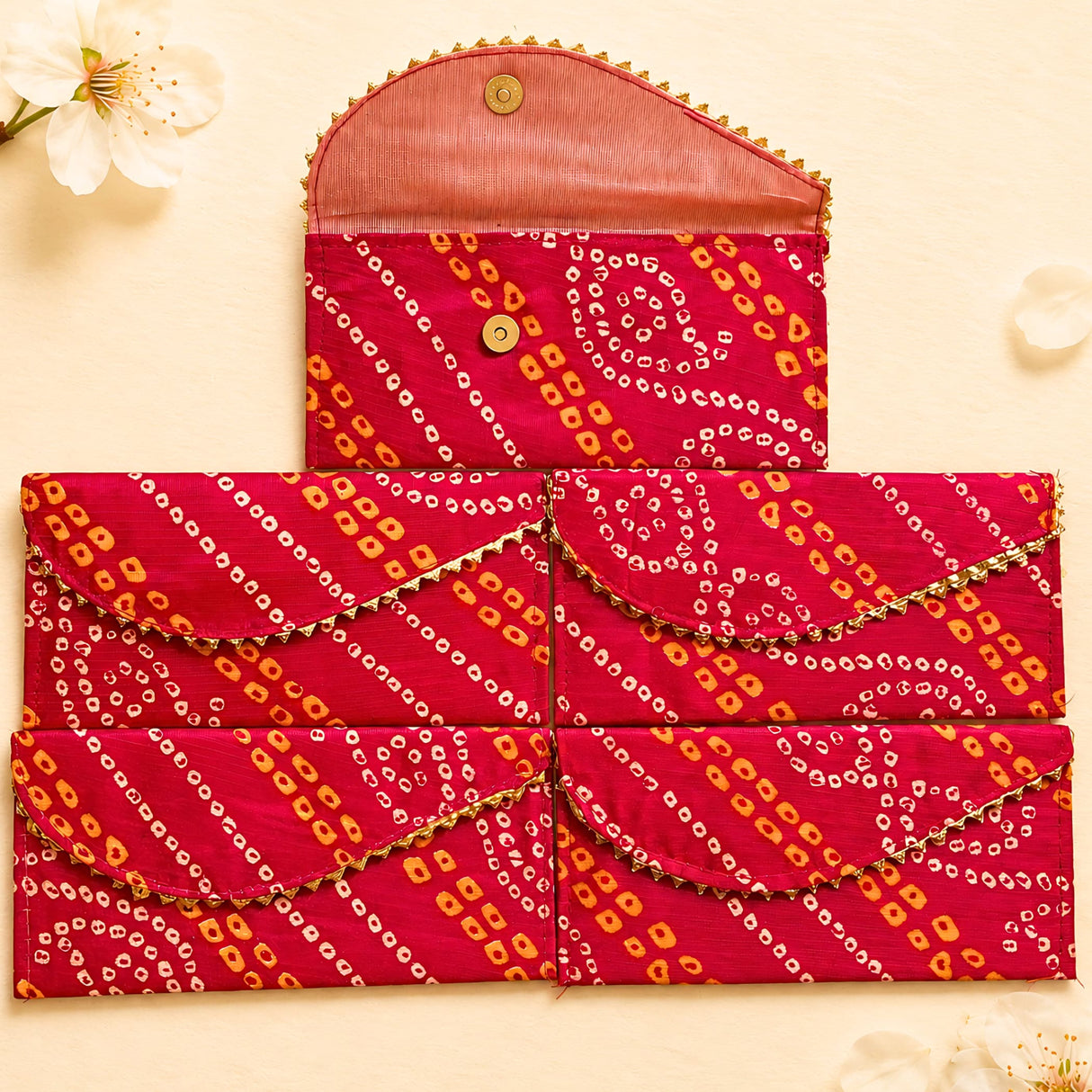 Brocade fabric money envelopes in vibrant red and orange with gold trim featuring decorative bandhani pattern