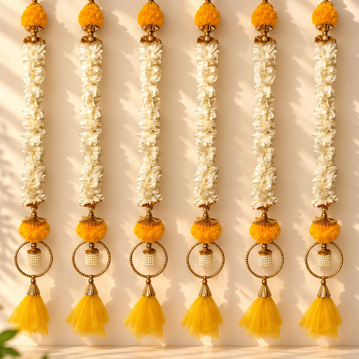 Bangle pom pom hanging backdrop garland with golden ornamental design, white jasmine flowers, and orange pom-poms for festive decor