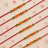 Designer bead rakhi with red cord orange beads and gold-toned leaf-shaped charms for brother and bhabhi gift