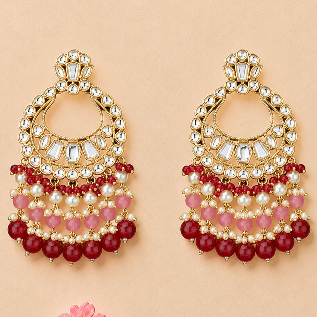 Elegant gold tone oversized Indian kundan chandelier earrings with clear stones, pink and red beads, and white pearls