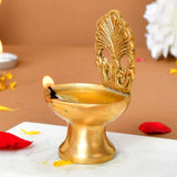 Golden brass diya with intricate fan-shaped lid and lit wick for traditional Hindu puja and Diwali home decoration