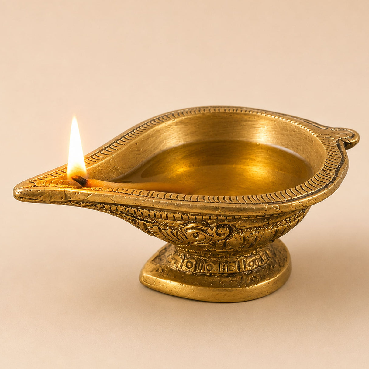 Golden brass diya oil lamp with intricate embossed patterns and lit wick for traditional hindu puja and home decoration