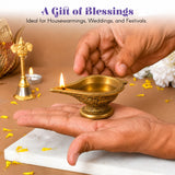 A golden brass diya oil lamp with intricate embossed patterns and lit flame for traditional Hindu puja and home decor