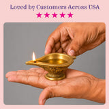 Golden brass diya oil lamp with intricate embossed patterns and lit wick for Diwali and traditional Hindu puja decor