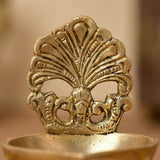 Golden brass diya oil lamp with intricate peacock feather design and ornate base for traditional Hindu puja and home decor