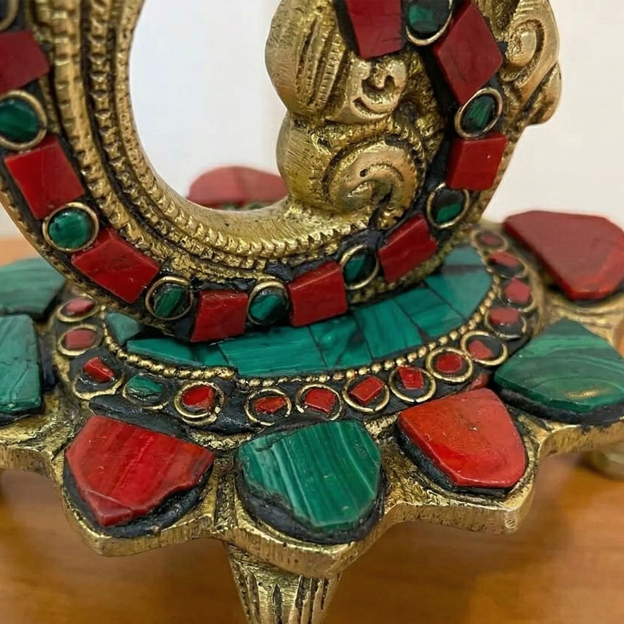 Golden ornate brass diya oil lamp with bells adorned with red and green gemstones for diwali puja decoration