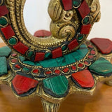 Golden ornate brass diya oil lamp with bells adorned with red and green gemstones for diwali puja decoration