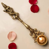 Golden brass decorative diya lamp with intricate deity carvings and floral handle designed for diwali and home decor