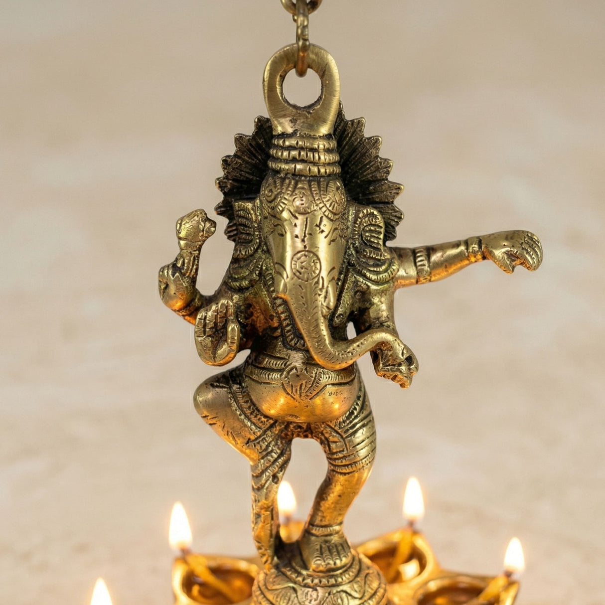 Golden brass ganesha wall hanging diya with intricate carvings, crown, bells, and lit oil lamps for diwali decor