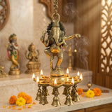 Golden brass ganesha wall hanging diya with nine lit candles and bells for home temple diwali decor and puja