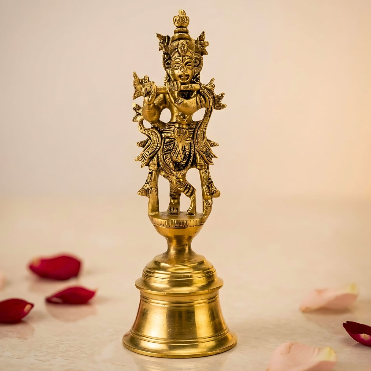 Golden brass figurine of lord krishna playing flute standing on ornate bell base for indian pooja and decor
