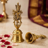 Golden brass krishna bell featuring a lord krishna figurine playing flute atop a traditional indian pooja bell