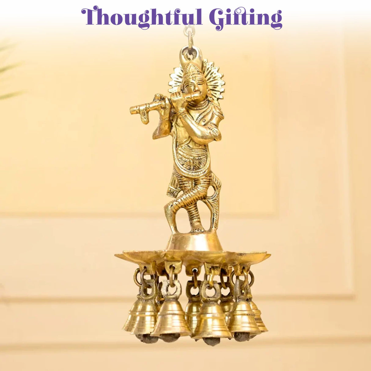 Golden brass figurine of lord krishna playing flute mounted on tiered base with five hanging bells for diya lamp decor