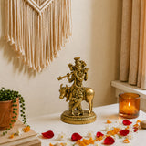 Golden brass statue of lord krishna riding a kamdhenu cow with ornate carvings for home temple decor and diwali pooja