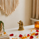 Golden brass figurine of lord krishna and radha standing on a decorative base for home temple pooja decor