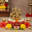 Golden brass Shiv Parivar idol with floral decorations on a red and gold base for home temple decor