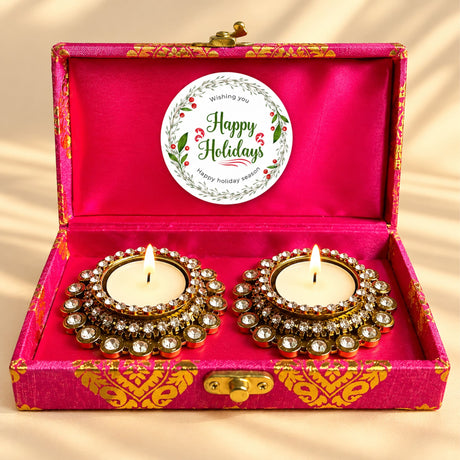 Two gold-toned crystal-studded diya holders with white candles in a pink satin-lined box festive gift set