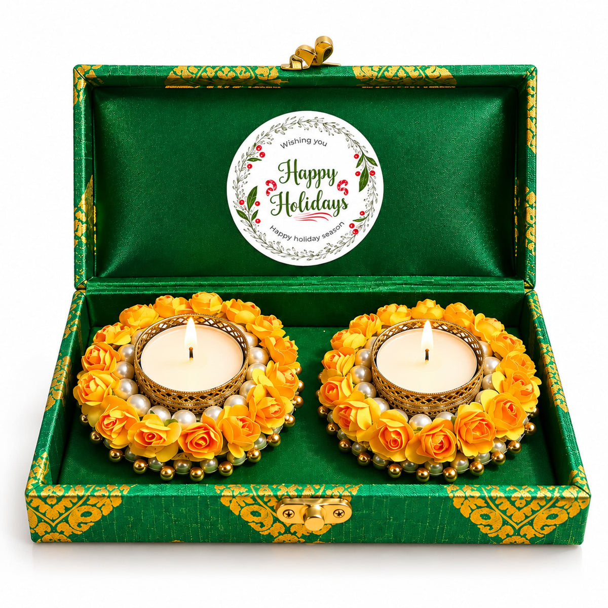 Two golden tealight candle holders decorated with yellow artificial roses and pearls in a green brocade gift box