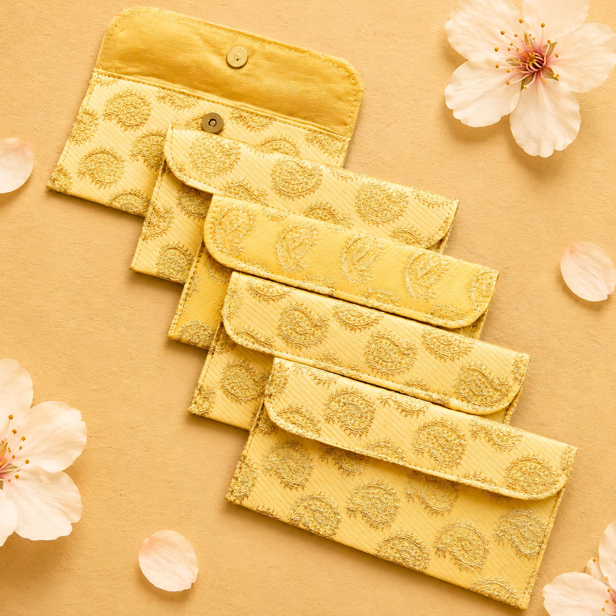 Set of five golden-yellow brocade fabric money envelopes with embroidered paisley pattern and metallic circular clasps