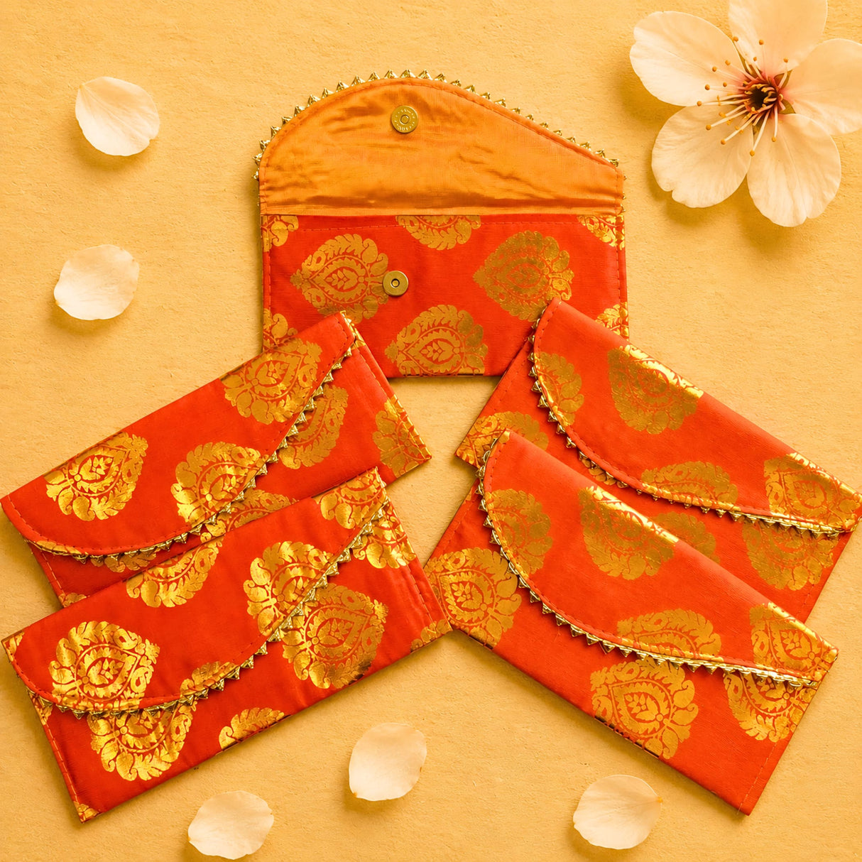 Vibrant orange brocade fabric money envelopes with intricate gold paisley patterns and decorative golden trim for cash gifts