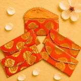 Vibrant orange brocade fabric money envelopes with intricate gold paisley patterns and decorative golden trim for cash gifts
