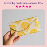 A cream brocade fabric money envelope with yellow floral pattern and gold-threaded edges for Indian wedding gifts