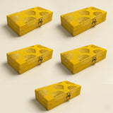 Bright yellow brocade gift boxes with gold leaf floral patterns and ornate clasps for indian wedding favors