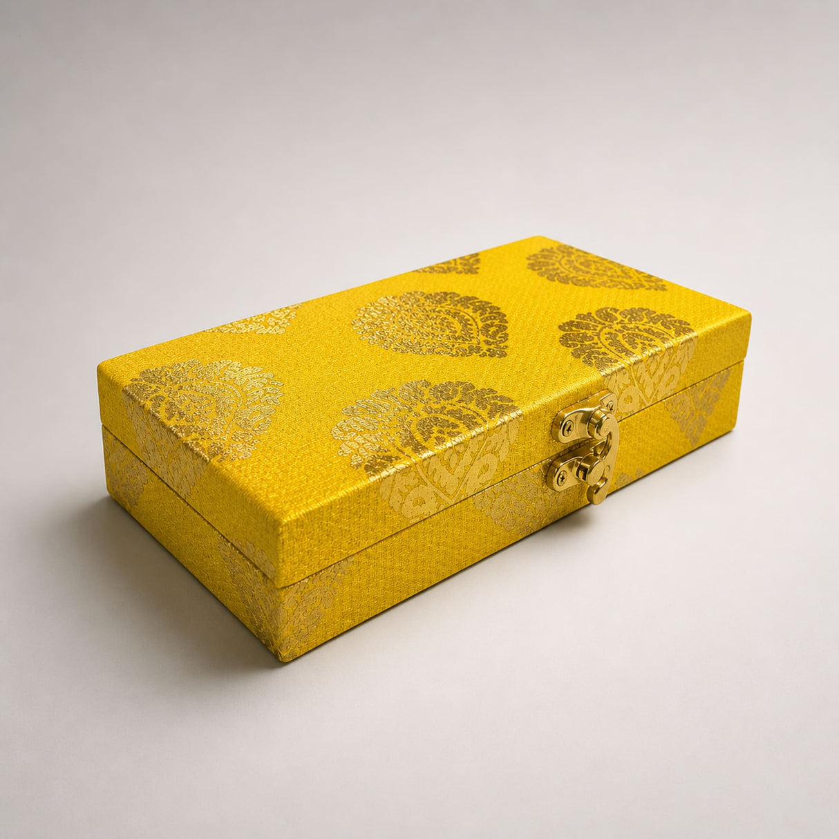 A rectangular golden-yellow brocade gift box with metallic gold paisley pattern and brass clasp for wedding favors
