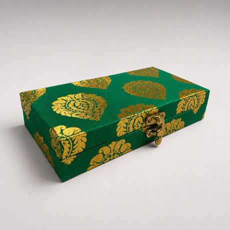 Green brocade gift box with gold leaf pattern and ornate brass clasp for Indian Muslim wedding favors