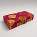 A rectangular magenta brocade fabric gift box with gold damask patterns and a brass clasp for indian weddings