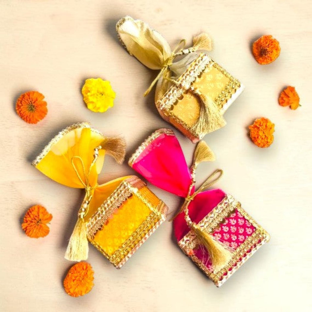 Three colorful brocade potli gift pouches with gold trim tassels organza top for traditional indian wedding favors