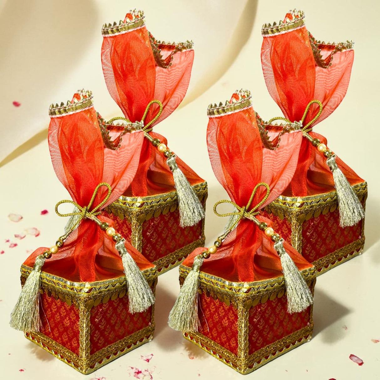 Red and gold brocade potli gift boxes with sheer red organza bows pearl beads and silver tassels for traditional indian weddings