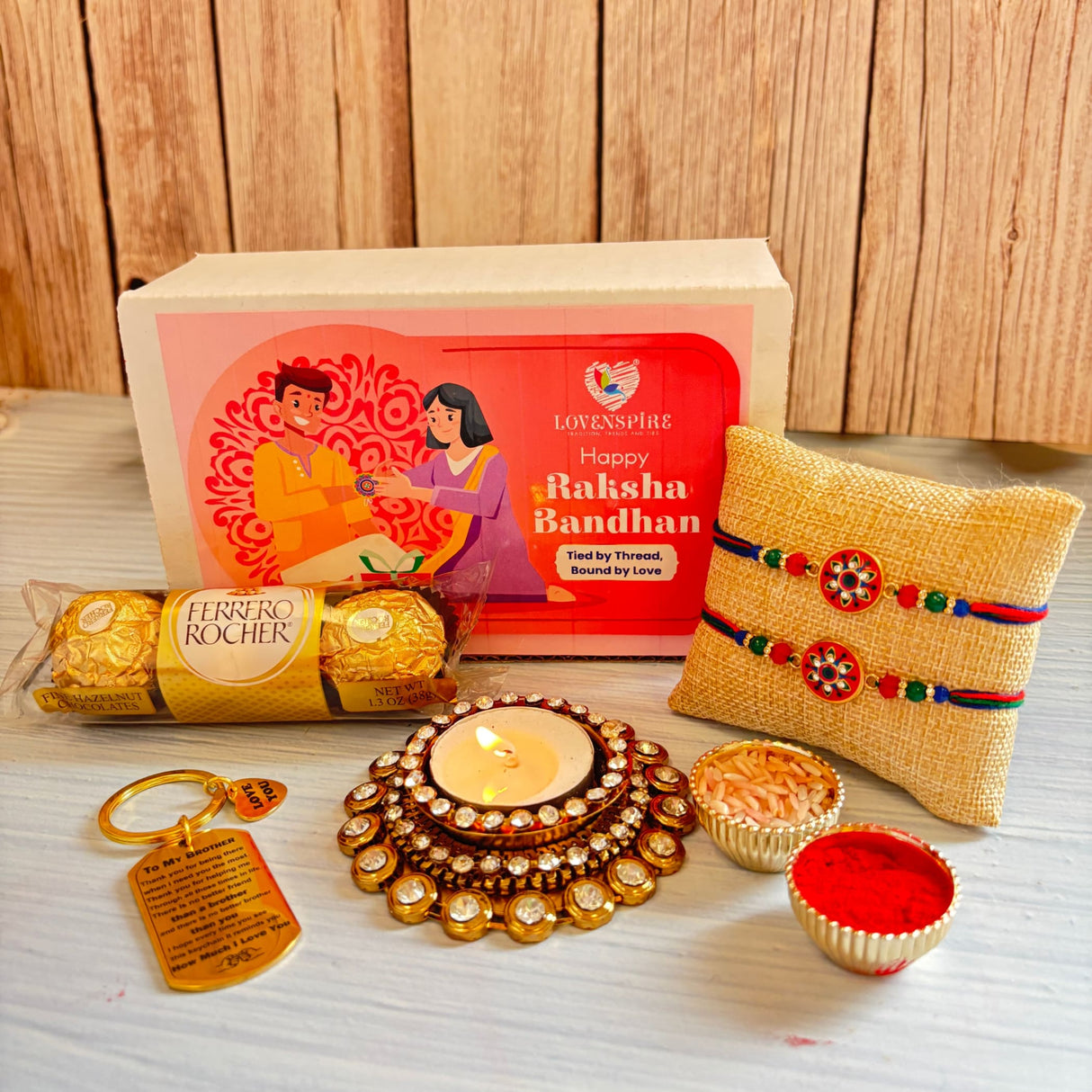Designer rakhi gift hamper with a gold-colored ornate diya featuring a lit candle and sparkling crystal embellishments