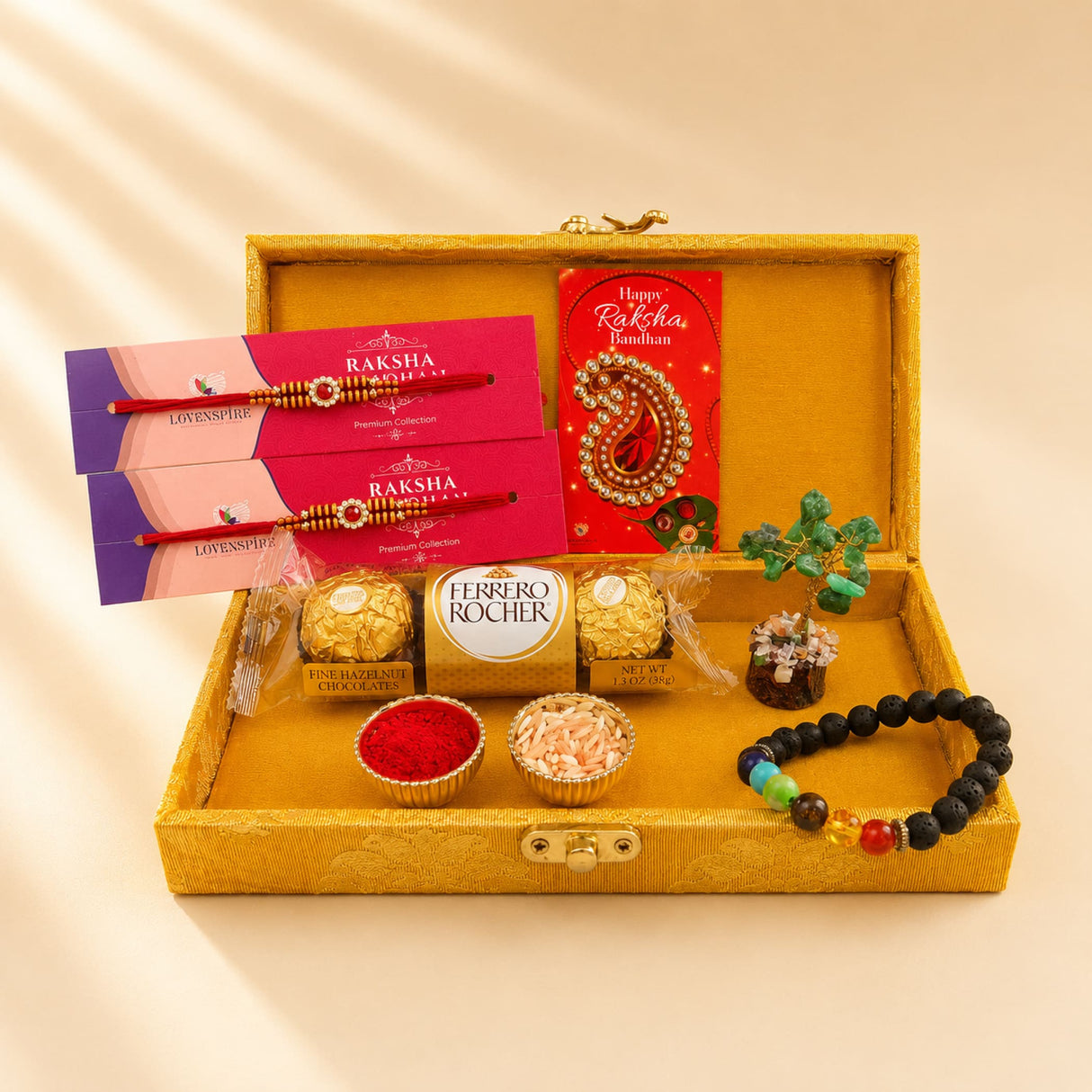 Designer rakhi gift hamper with golden ornate box containing red and gold rakhis, chakra bracelet, chocolates, roli chawal, and crystal tree