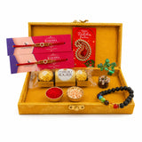 Golden ornate designer rakhi gift hamper with red and gold rakhis, chakra bracelet, crystal tree, chocolates, and colored powders