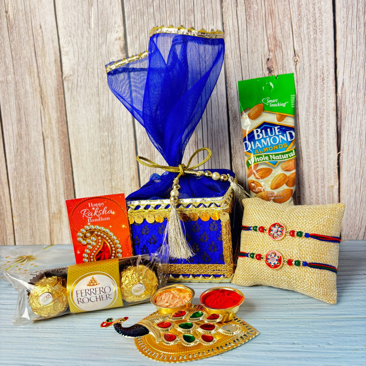 Designer rakhi gift hamper set featuring a blue and gold embroidered gift box with sheer blue organza cover and golden ribbon