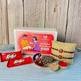 Gold-colored peacock-shaped designer rakhi with intricate red and green gemstones in gift hamper set for brother and bhabhi