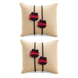 Beige burlap pillow with two red plastic train charms and black cord ties in cartoon rakhi for brother set