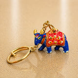 Handmade ceramic cow shaped keychain in vibrant blue and red with gold accents for Indian good luck charm and gifts