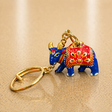 Handmade ceramic cow shaped keychain in vibrant blue and red with gold accents for Indian good luck charm and gifts