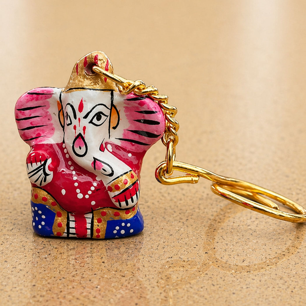 Handmade ceramic ganesha amulet keychain with vibrant pink red and blue accents and gold chain for housewarming gifts