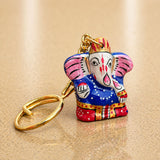 A vibrantly painted handmade ceramic Ganesha keychain with pink blue red and gold accents for return gifts and bags