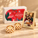 Pearl-encrusted gold tea light holders with lit candles in a festive christmas gift hamper with customizable photo frame